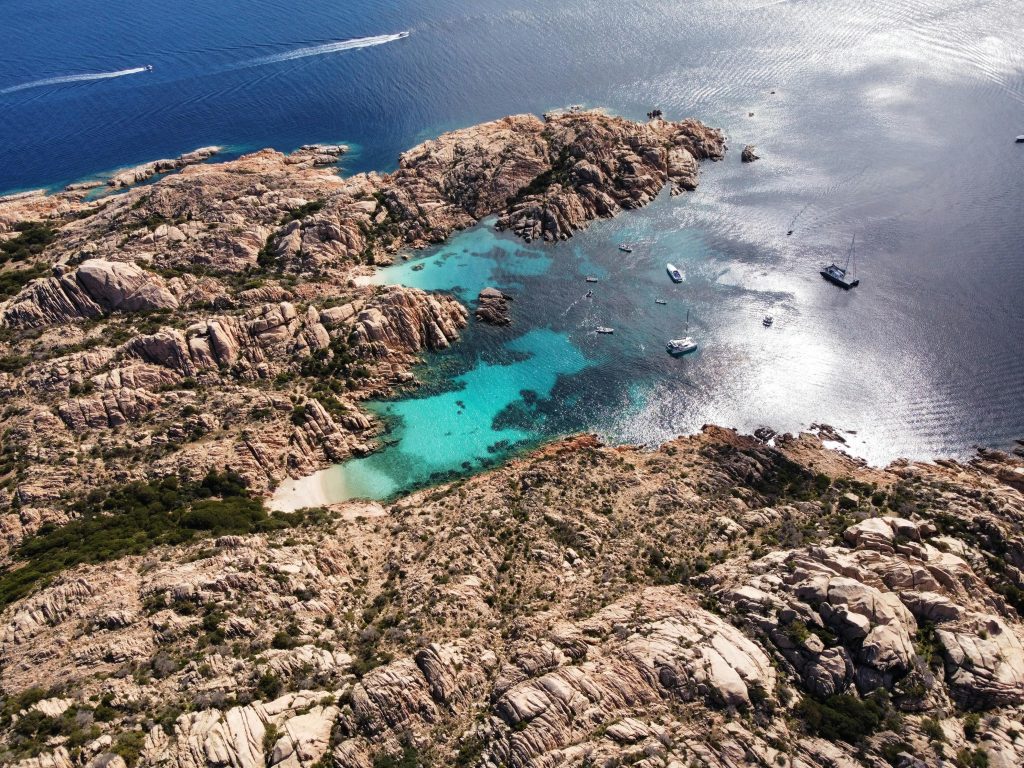 Stunning aerial view of turquoise waters and rugged coastline in La Maddalena Archipelago, Sardinia.