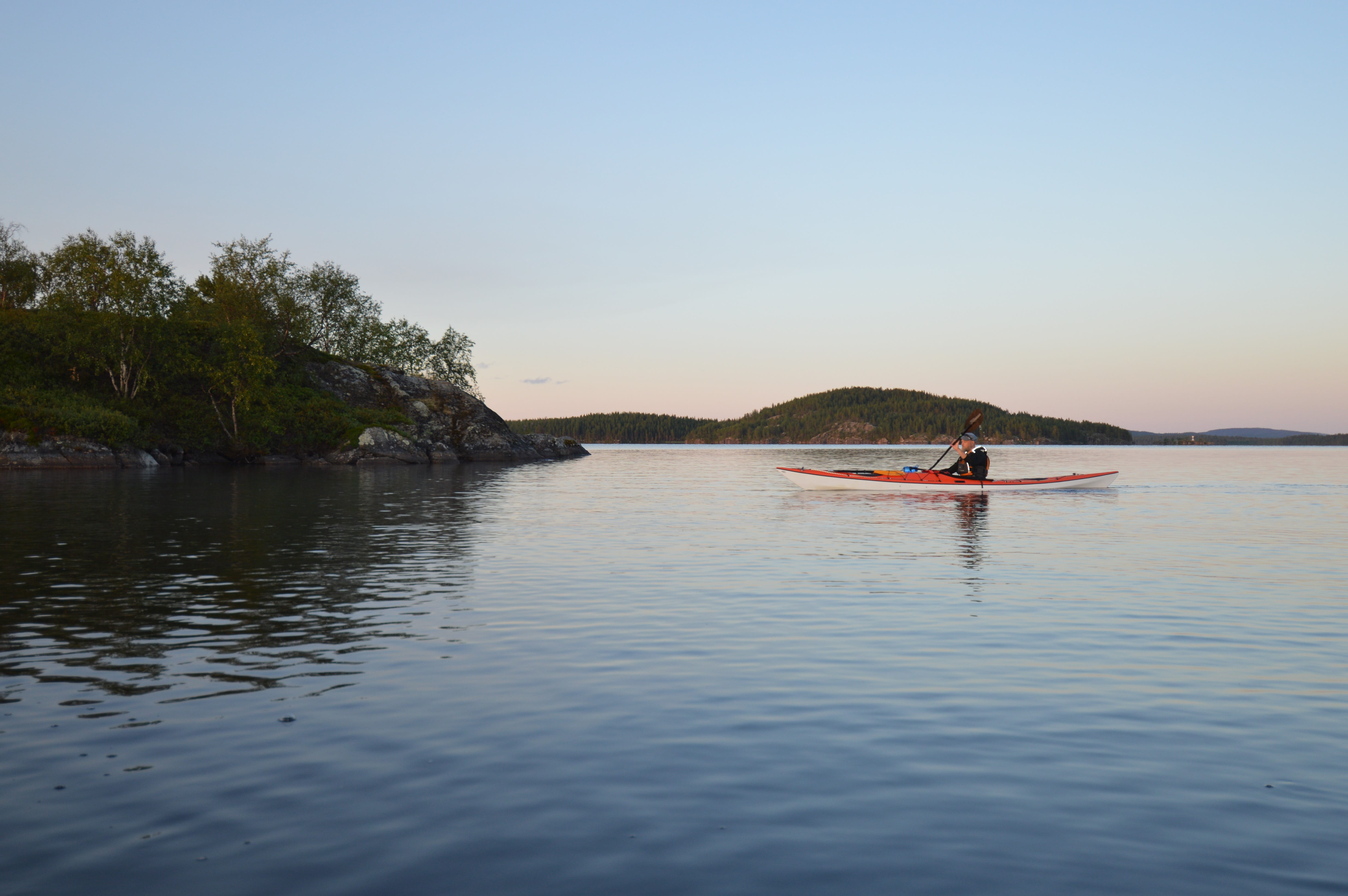 Kayaking on a calm lake in the soft light of a Lapland summer evening