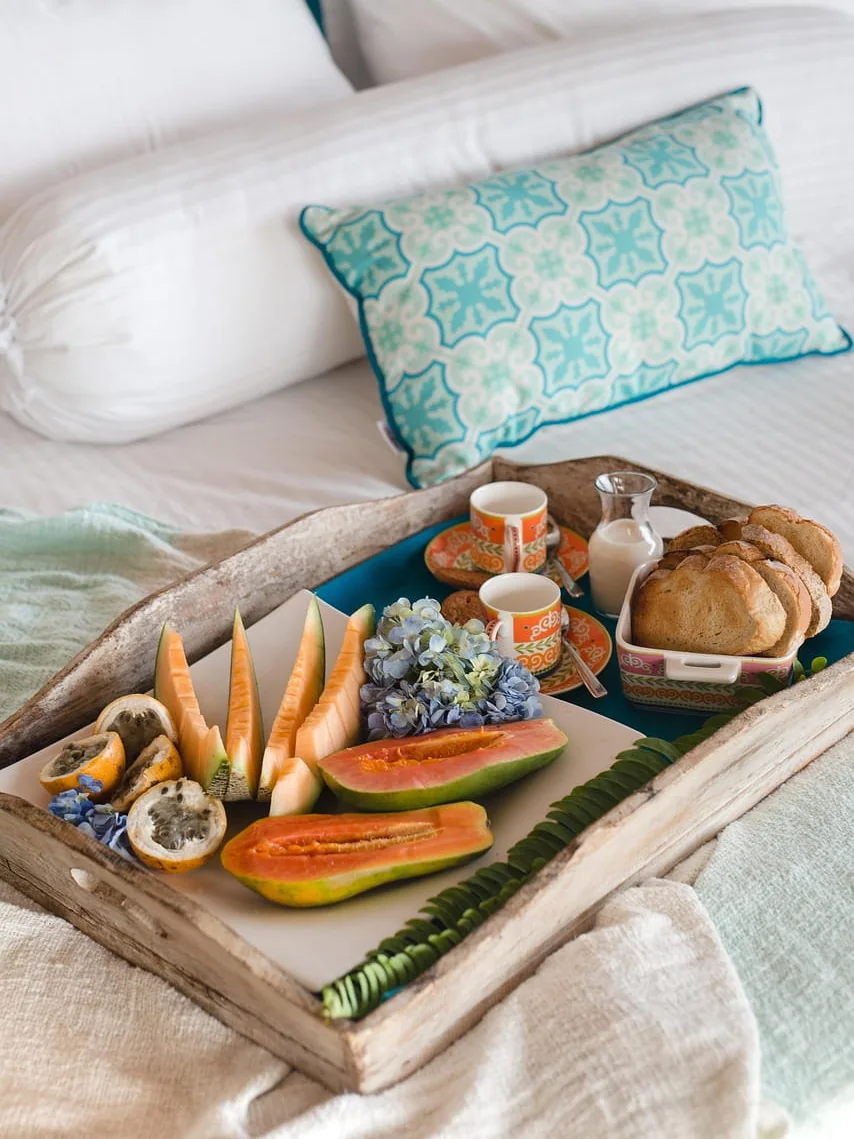 Breakfast tray of fresh fruit and coffee on a luxury hotel bed
