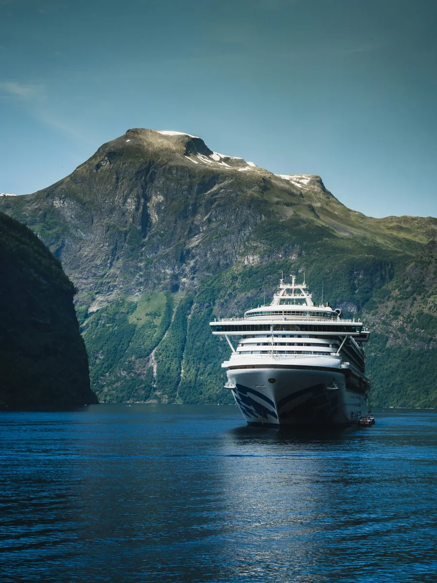 Cruise ship in a fjord beneath green mountains, cruise planning with Blue Turtle Escapes