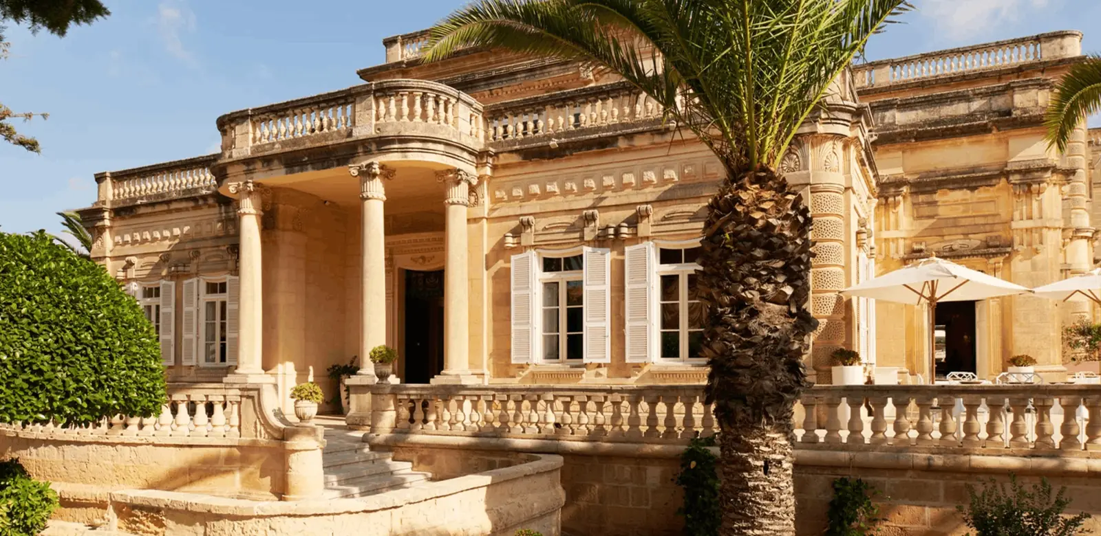 The honey-stone columned facade and terrace of Corinthia Palace Malta in Attard