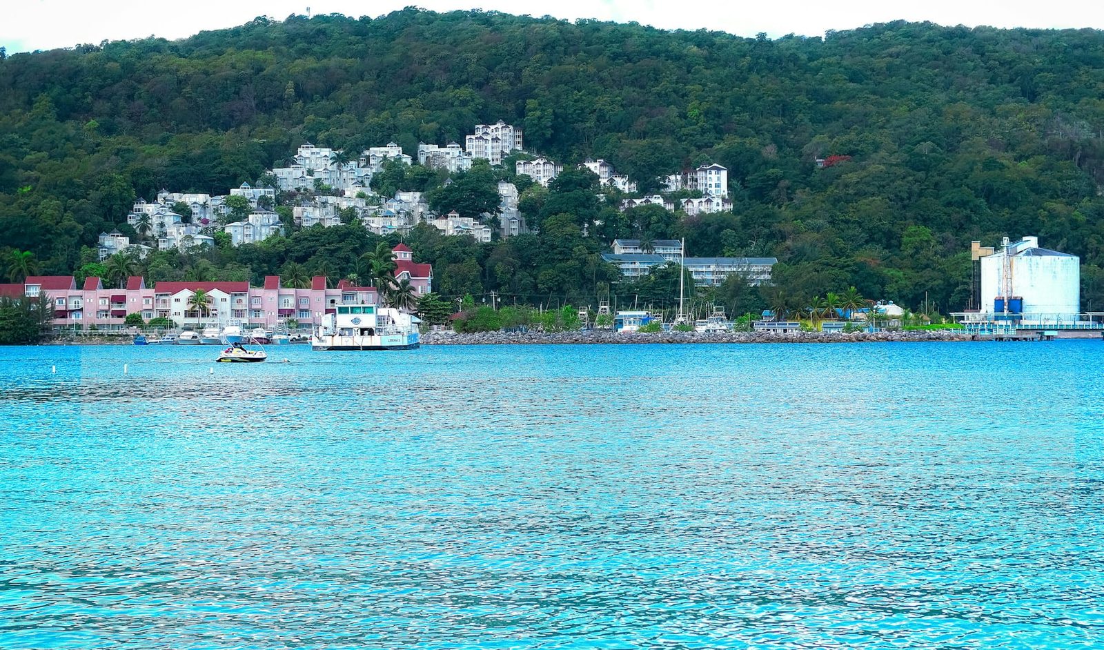 A Caribbean harbour with boats and hillside buildings above turquoise water