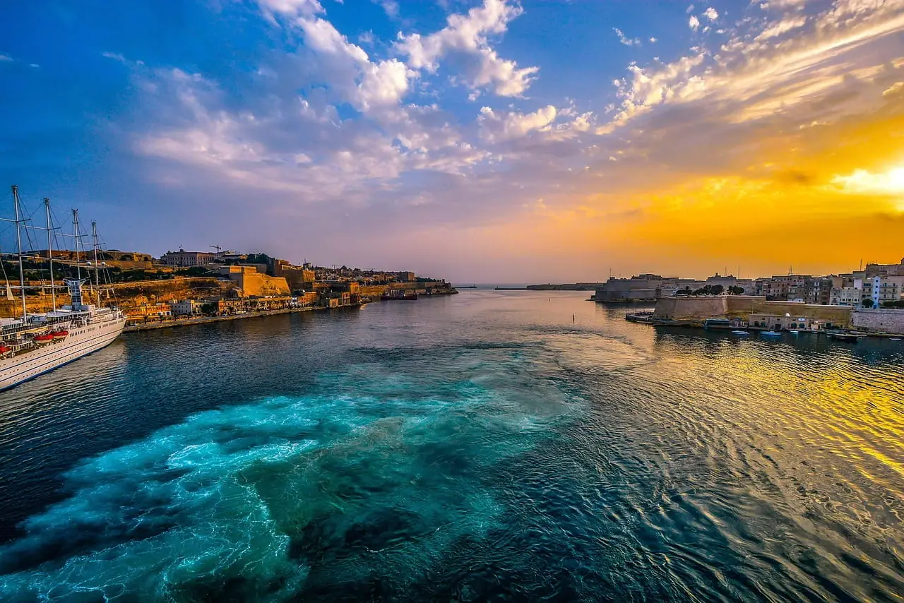 A cruise ship departing Valletta's Grand Harbour past the fortifications at sunset, Malta
