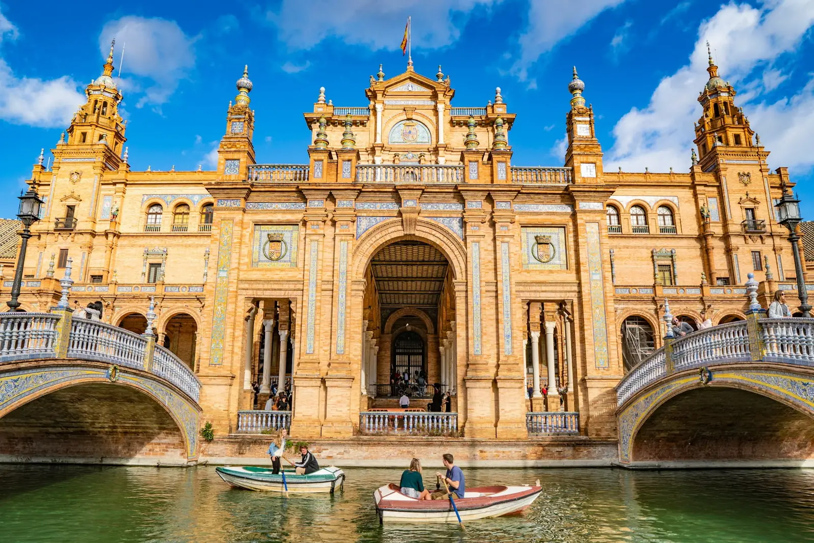 Couples in rowing boats on the canal beneath the Plaza de Espana in Seville, Spain