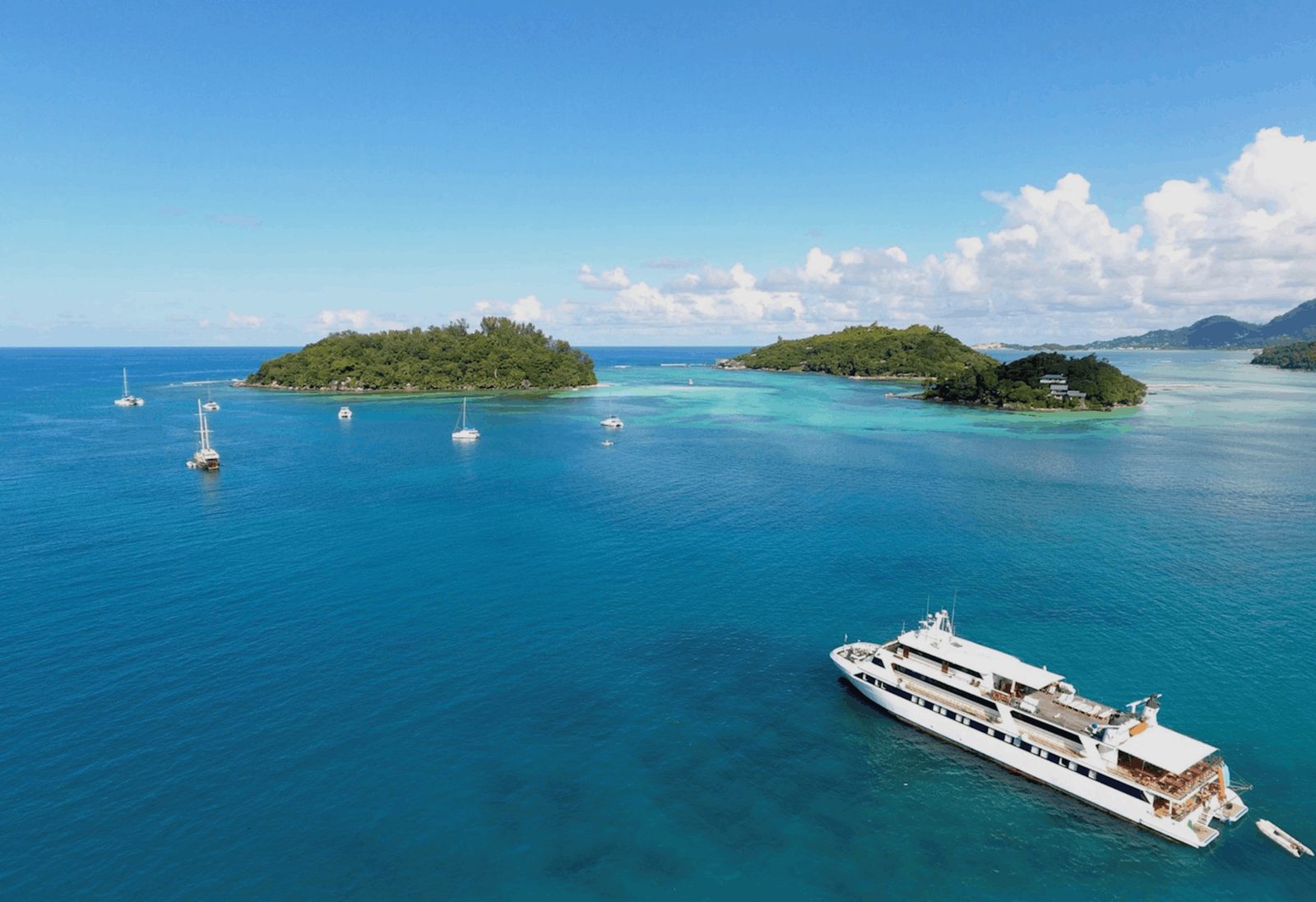A small cruise ship anchored beside a granite-framed inner island in the Seychelles