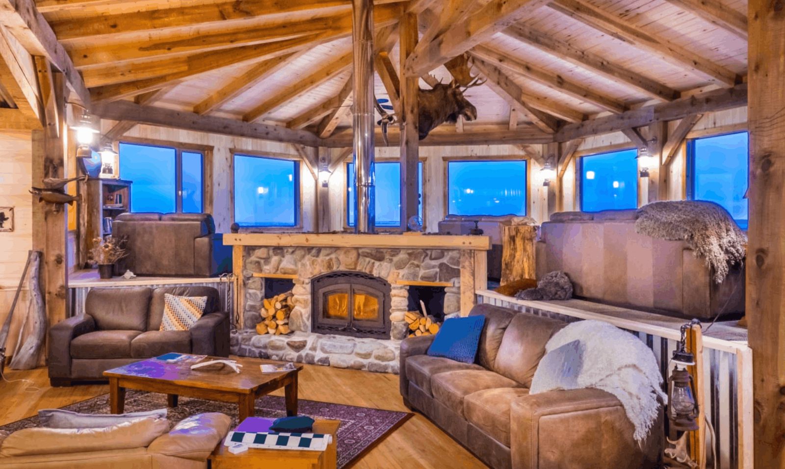 The timber lounge and stone fireplace at Seal River Heritage Lodge, with windows onto Hudson Bay, Manitoba
