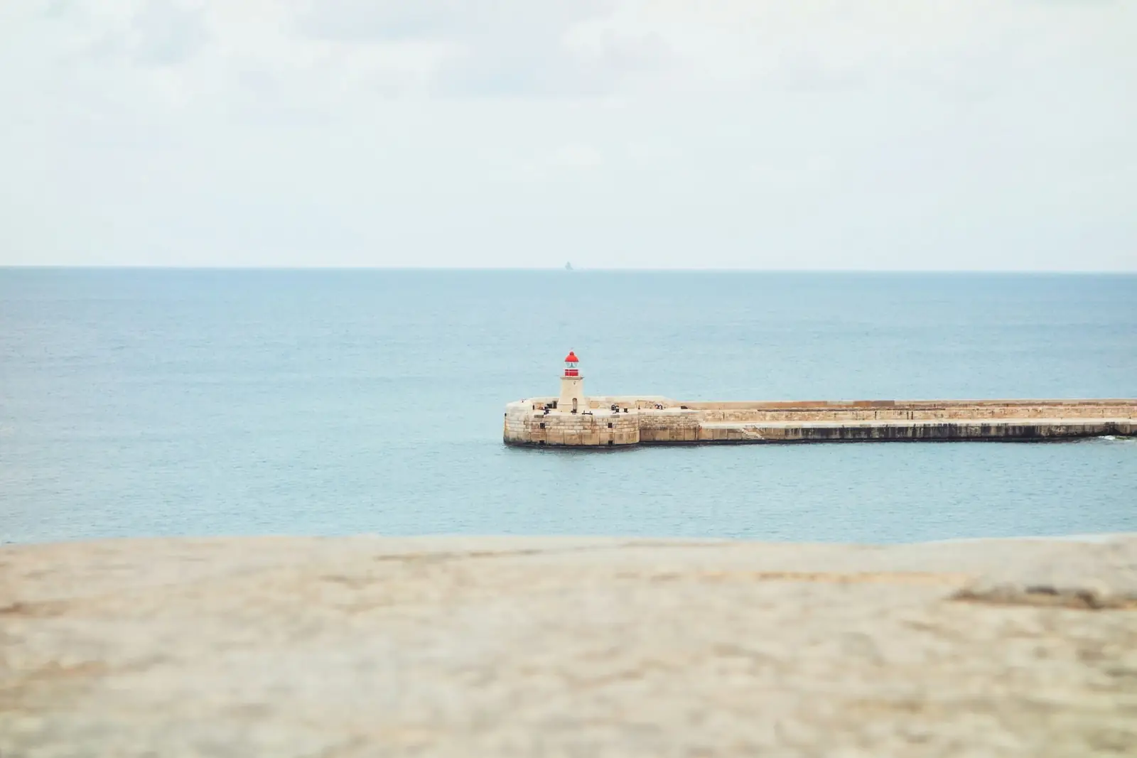 The red and white lighthouse on the breakwater at the entrance to Valletta's Grand Harbour, Malta