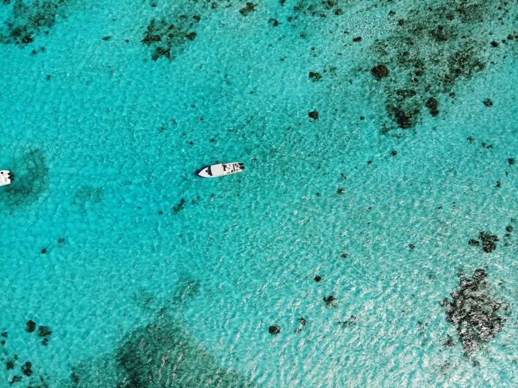 Belize holidays. Stunning aerial view of white boats on the clear, turquoise waters of Belize, showcasing marine life.
