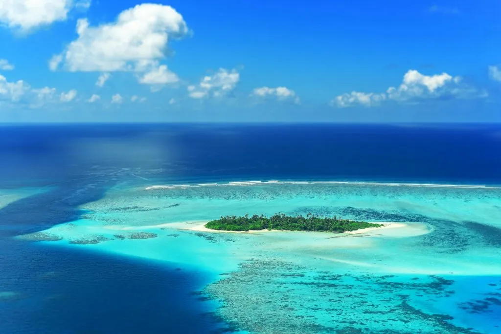 Indian Ocean Cruises. A stunning aerial view captures a lush island surrounded by turquoise waters in the Maldives.