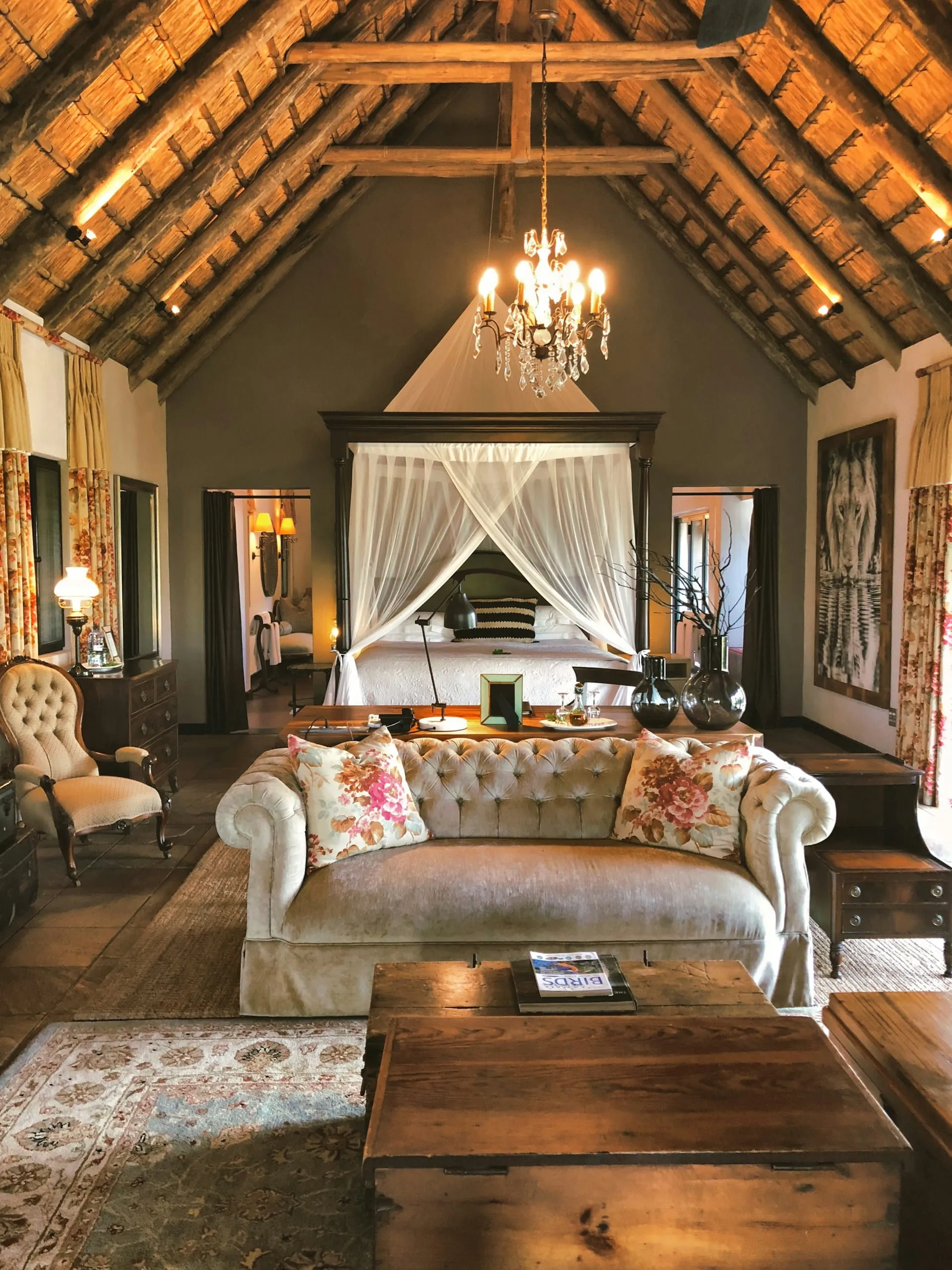 A thatched safari lodge suite with a four-poster bed and sitting area in South Africa