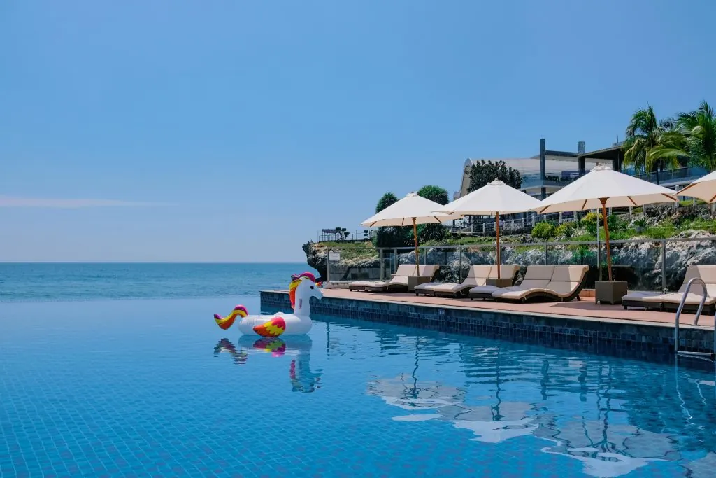 Infinity pool with unicorn float overlooking ocean, ideal for summer vacation and leisure.