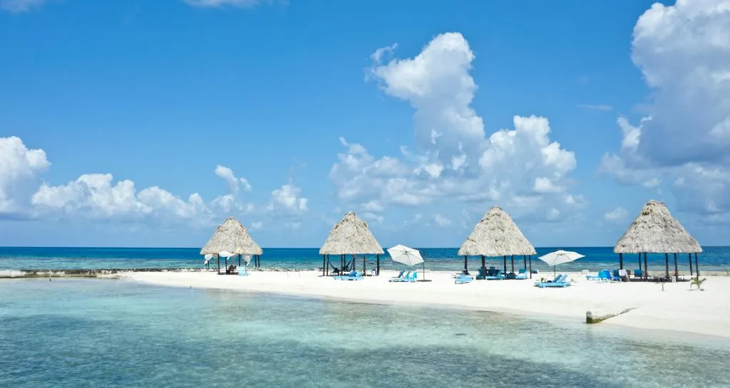 Peaceful tropical beach with palapas on a sunny day in Belize.