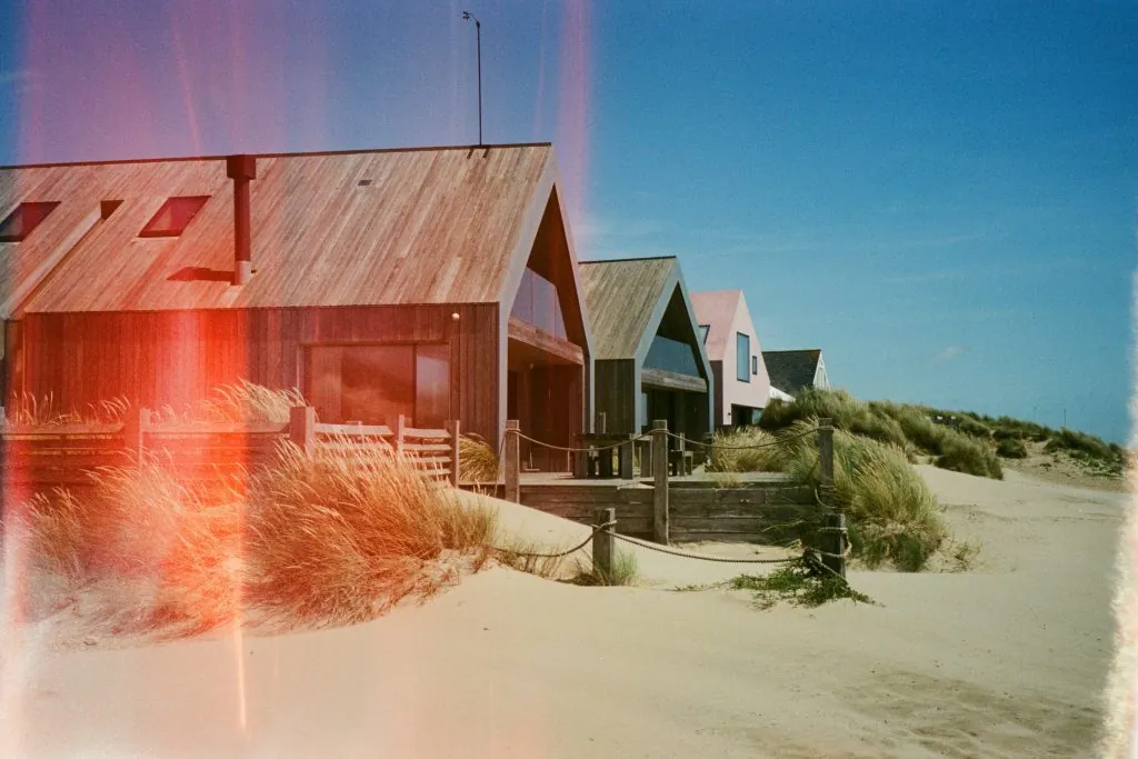 Rustic beach houses at Camber Sands in England, with warm sand dunes and a summer atmosphere.