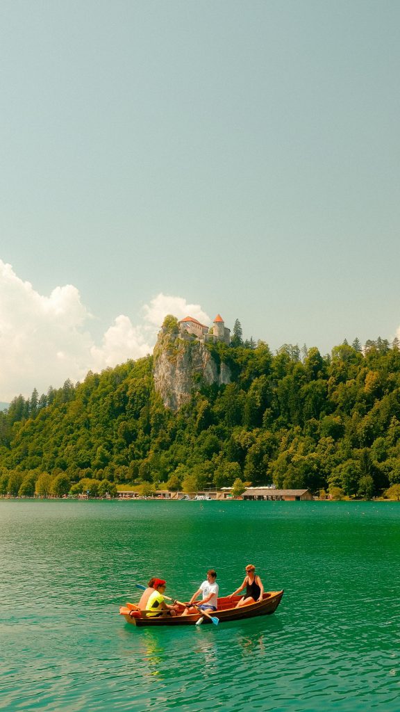 Scenic view of Lake Bled with tourists boating under the iconic Bled Castle in Slovenia.