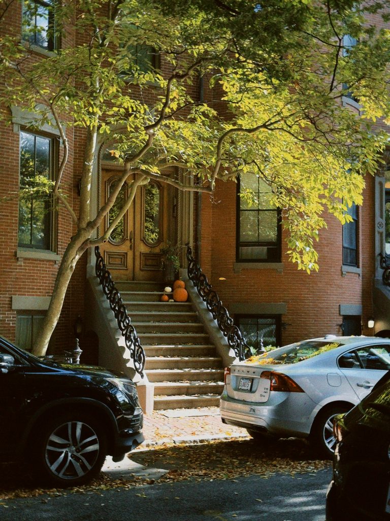 Historic Boston brownstone entrance adorned with pumpkins and fall foliage.