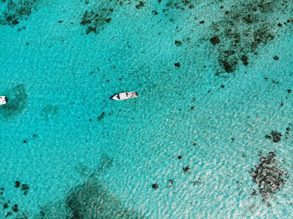 Belize holidays. Stunning aerial view of white boats on the clear, turquoise waters of Belize, showcasing marine life.